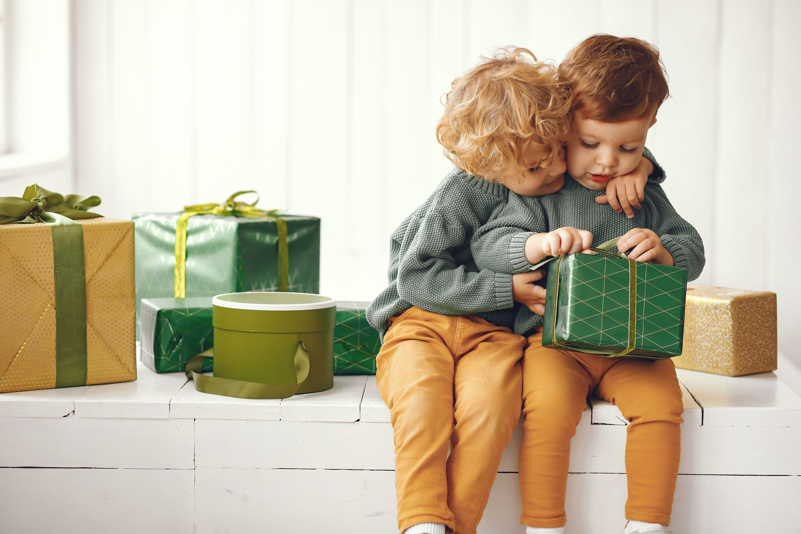 Little kids near christmas tree in a gray sweater